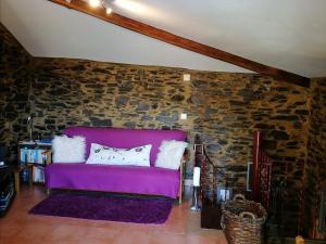 um sofá roxo num quarto com uma parede de pedra em Bela Vista Alqueve - 2 houses with pool, 2 casas com piscina em Arganil