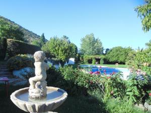 a stone fountain in a garden with a swimming pool at Hostal El 402 in Iznalloz