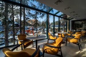 un restaurante con sillas amarillas, mesas y ventanas en Mona Plaza Zlatibor en Zlatibor