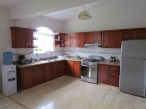 a kitchen with wooden cabinets and a stainless steel refrigerator at Villa Sosua Hispaniola Residencial in Sosúa