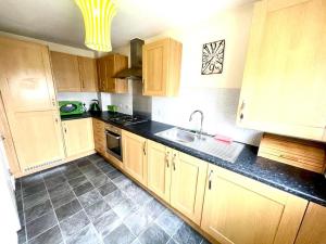 a kitchen with wooden cabinets and a black counter top at Lakeside Stylish 3 Bedroom House in Grays Thurrock
