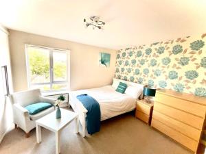 a small bedroom with a bed and a chair at Lakeside Stylish 3 Bedroom House in Grays Thurrock