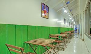a row of tables and chairs in a green wall at Treebo Trend Blue Dawn Gachibowli in Hyderabad