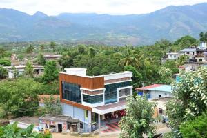a building in a town with mountains in the background at Hotel Magnet in Maraiyūr