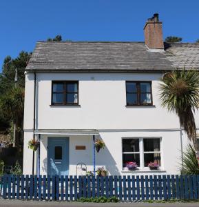 a white house with a blue fence at Tulloch (2 Hamilton Place) in Kyle of Lochalsh