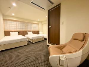 a hotel room with two beds and a chair at Kadoya Hotel in Tokyo