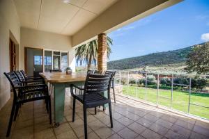 a dining room with a table and chairs on a balcony at Vredehoek Guest Farm in Breerivier