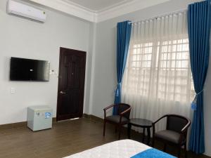 a bedroom with a bed and two chairs and a television at Khách sạn Hoàng Minh Châu Mỹ Phước in Bến Cát