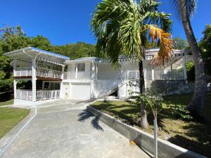 una casa blanca con una palmera delante de ella en Coco-Mango Apt C, en Deshaies