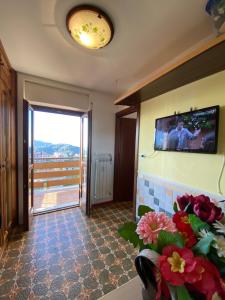 a living room with a tv on the wall and flowers at Bilocale condominio del sole in San Giacomo