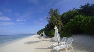 ein Strand mit Stühlen und einem Sonnenschirm und das Meer in der Unterkunft Coco Villa Ukulhas in Ukulhas