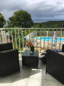 un patio con sillas y una mesa con vistas a la piscina en La Nicotoria Apartments, en Deshaies
