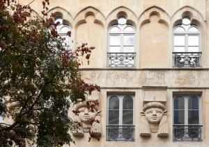 two heads on the side of a building with windows at H&ocirc;tel du Sentier in Paris