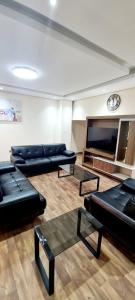 HAVANA HOLIDAY HOMES MIRDIF في دبي: غرفة معيشة مع كنب وتلفزيون بشاشة مسطحة