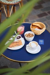 a blue table with plates of food and a basket of bread at Hôtel du Sentier in Paris