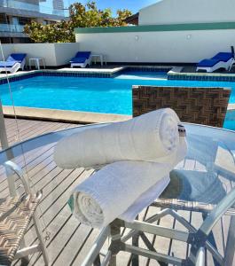 dos toallas enrolladas sentadas en una mesa junto a una piscina en Pousada La Barca en Torres
