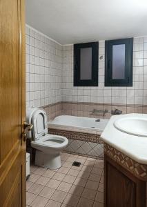 a bathroom with a toilet and a tub and a sink at Spacious House in a Quiet Neighbourhood in Ierapetra