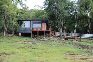 uma pequena casa sentada num campo ao lado de uma cerca em Rancho VSS Cabana da Montanha 1 em Nova Petrópolis