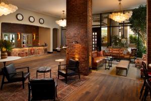 un hall avec des chaises et des tables ainsi qu'un mur en briques dans l'établissement Hotel ZaZa Austin, à Austin