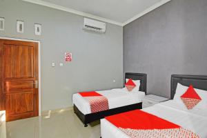 1 Schlafzimmer mit 2 Betten mit roter und weißer Bettwäsche in der Unterkunft Super OYO 90767 Gm Guest House in Wonogiri