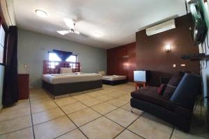Habitación grande con cama y sofá en Hotel Colonos Los Cabos, en Cabo San Lucas