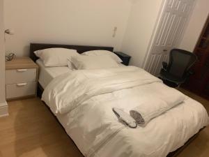 a bed with white sheets and a chair in a bedroom at Lovely room, free parking in private gated place in London