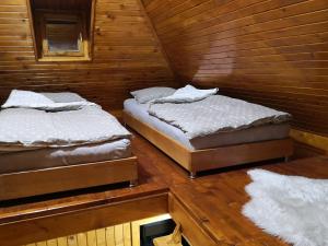 two twin beds in a room with wooden walls at Vikendica Ajla in Travnik