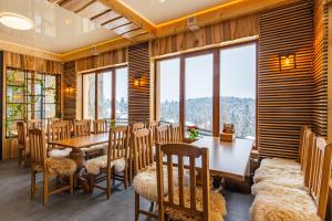 a dining room with a table and chairs and windows at Rich OAK - готель з відкритим панорамний басейном in Yablunytsya