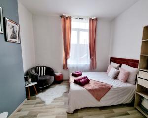 um quarto com uma cama, uma cadeira e uma janela em Oasis Citadine Terrasse intime jardin privatif en plein centre ville 70m2 em Cambrai