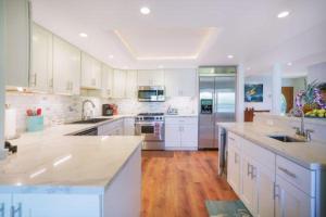 a large kitchen with white cabinets and wooden floors at Luxury 2-Story Oceanfront Condo w/ Views & Pool in Wailua