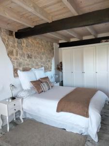 a bedroom with a large white bed and a stone wall at La buganvilla en Udías in Udias