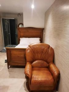 a bedroom with a bed and a brown leather chair at Chambre meublée indépendante, jacuzzi dans la chambre à 60110 Amblainville près de Paris in Amblainville +17 photos