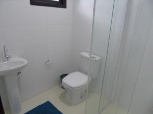 a white bathroom with a toilet and a shower at Mare de Lua Boraceia in Boracéia