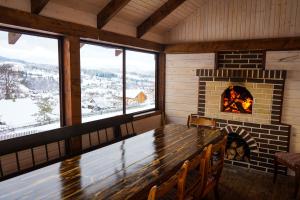 a room with a fireplace and a table and chairs at Zatyshok v Karpatah 2 in Vorokhta