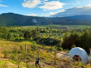 a view of a farm from a hill with a tent at Glamping NIDO VERDE in Iza