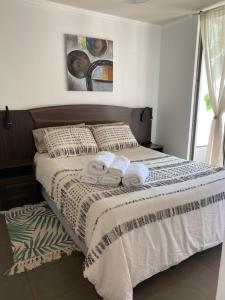 a bedroom with a bed with two towels on it at Departamento entero Reñaca - Jardín del mar in Viña del Mar