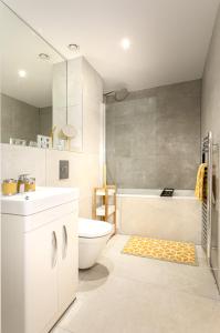 a bathroom with a tub and a toilet and a sink at The Arches Watford Serviced Apartment in Watford