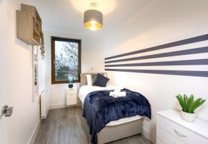 The Arches Watford Serviced Apartment في واتفورد: غرفة نوم بسرير عليها بقع زرقاء وبيضاء