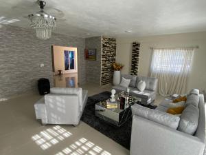 una sala de estar con muebles blancos y una lámpara de araña. en Villa La Grande, en Jarabacoa