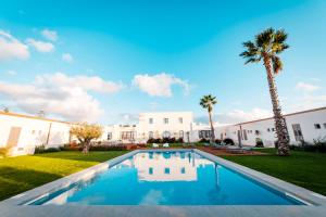una piscina davanti a una casa con una palma di Baglio Custera a Marsala