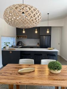 a kitchen with a wooden table and a large pendant light at The Little House in Inverloch