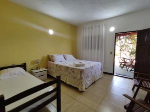 a bedroom with two beds and a door to a patio at Pousada Vila Sol in São Miguel do Gostoso