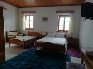 a bedroom with two beds and a couch and windows at Hotel Tymfi in Tsepelovo