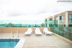 a balcony with white chairs and a pool on a building at Brand New - Prime Location For All Budgets - Executive & Luxury in Barranquilla
