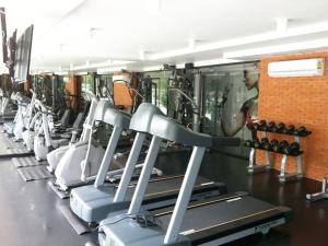 a gym with rows of tread machines and a man in the background at Marigold Ramkhamhaeng in Bangkok