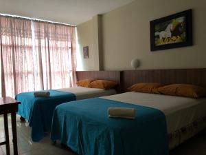 ein Hotelzimmer mit 2 Betten und einem Fenster in der Unterkunft Luz de Aurora HOTEL in Manta