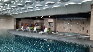 a swimming pool in a building with chairs and a table at Studio Above The Cloud at Ion Element Genting in Genting Highlands