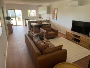 ein Wohnzimmer mit einem braunen Sofa und einer Küche in der Unterkunft House on Argent Street in Broken Hill