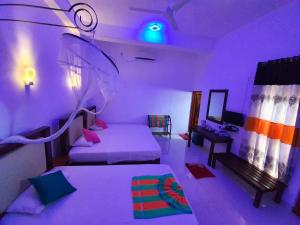 1 dormitorio con 2 camas y luz morada en Peacock Reach Hotel, en Tissamaharama