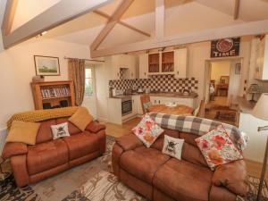 a living room with two couches and a kitchen at Old Tether Barn in Whitechurch